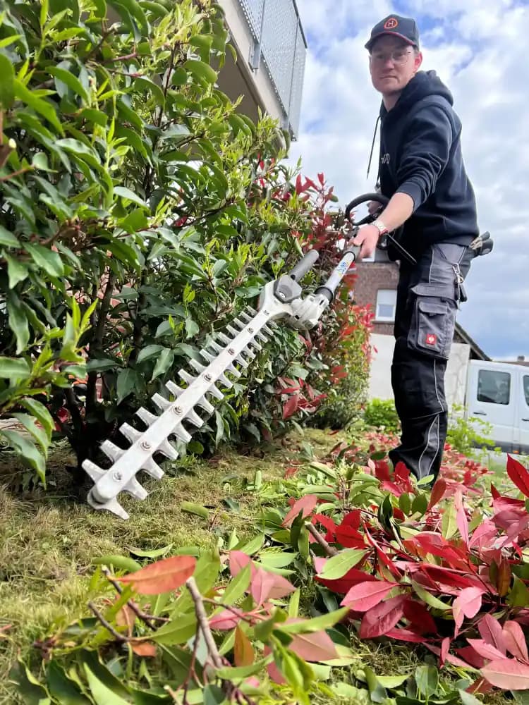 Hausmeister bei der Gartenpflege an einer gepflegten Immobilie